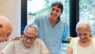 A smiling psychiatric-mental health registered nurse engages participants in group therapy.